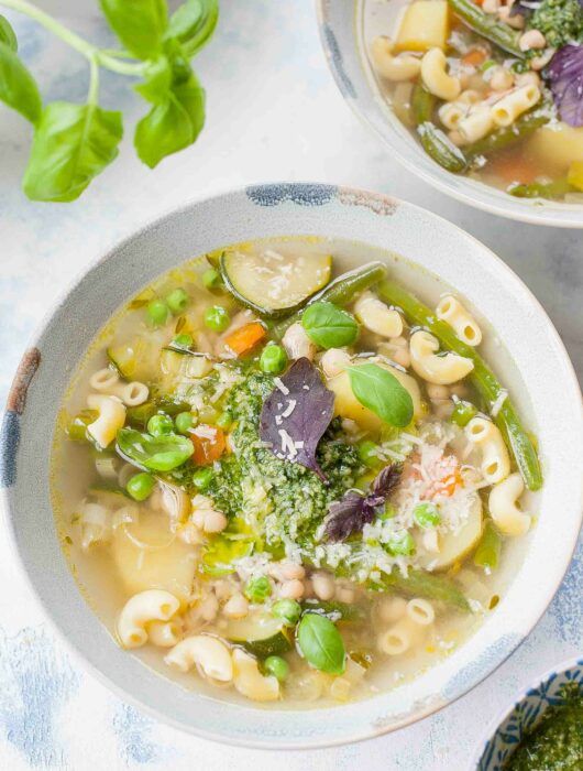 Soupe au pistou in a blue bowl garnished with basil leaves.