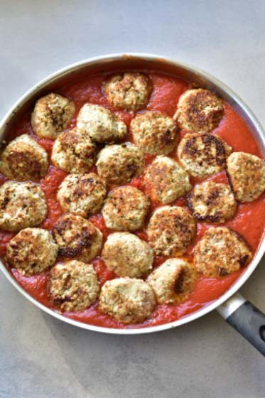 ricotta meatballs are being simmer in tomato sauce