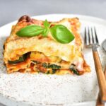 A piece of zucchini spinch lasagna on a white plate.