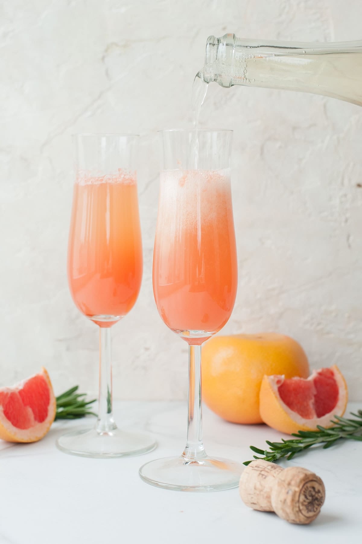 Two champagne glasses filled with grapefruit mimosa.
