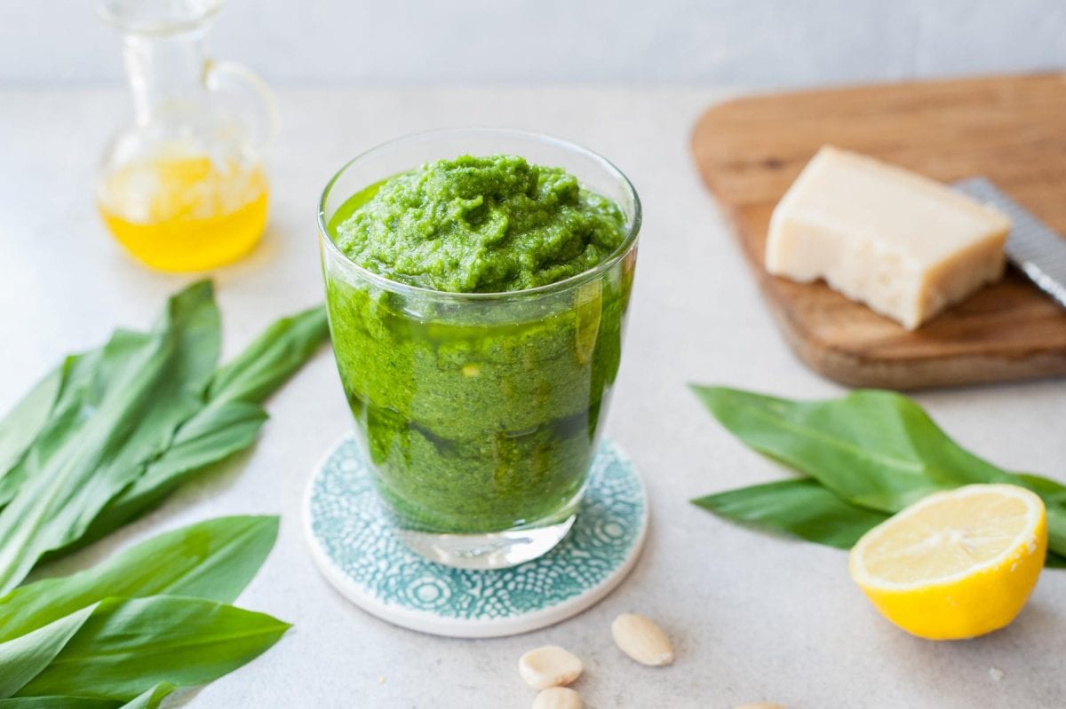 Wild garlic pesto (ramp pesto) in a glass, wild garlic leaves scattered around.