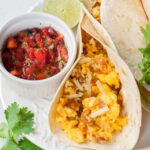 Scrambled eggs tacos with pico de gallo salsa on a plate.