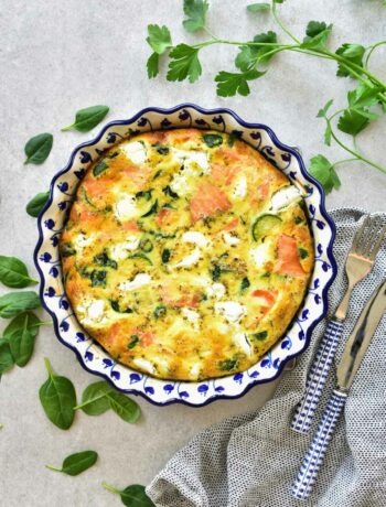 Smoked salmon frittata with zucchini and spinach in a white-blue baking dish.