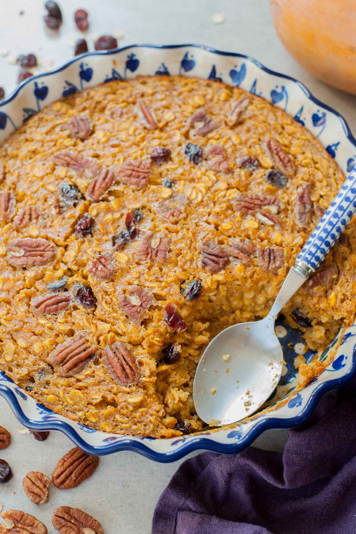A close up picture of baked pumpkin oatmeal in a baking dish with a serving missing.
