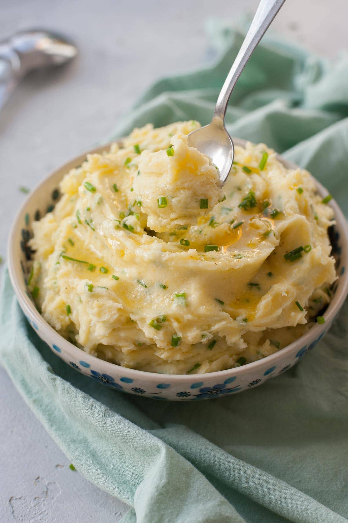 Sour cream mashed potatoes with chives in a white-blue bowl.