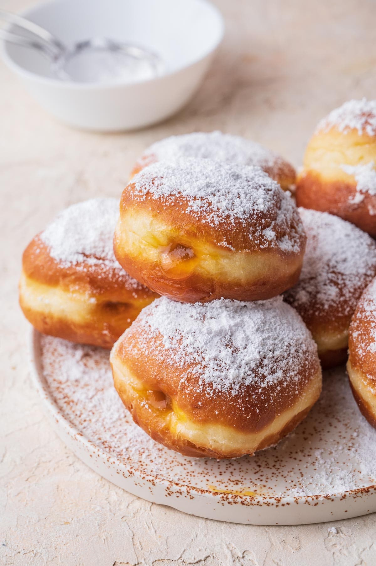 Krapfen dusted with powdered sugar on a white plate.