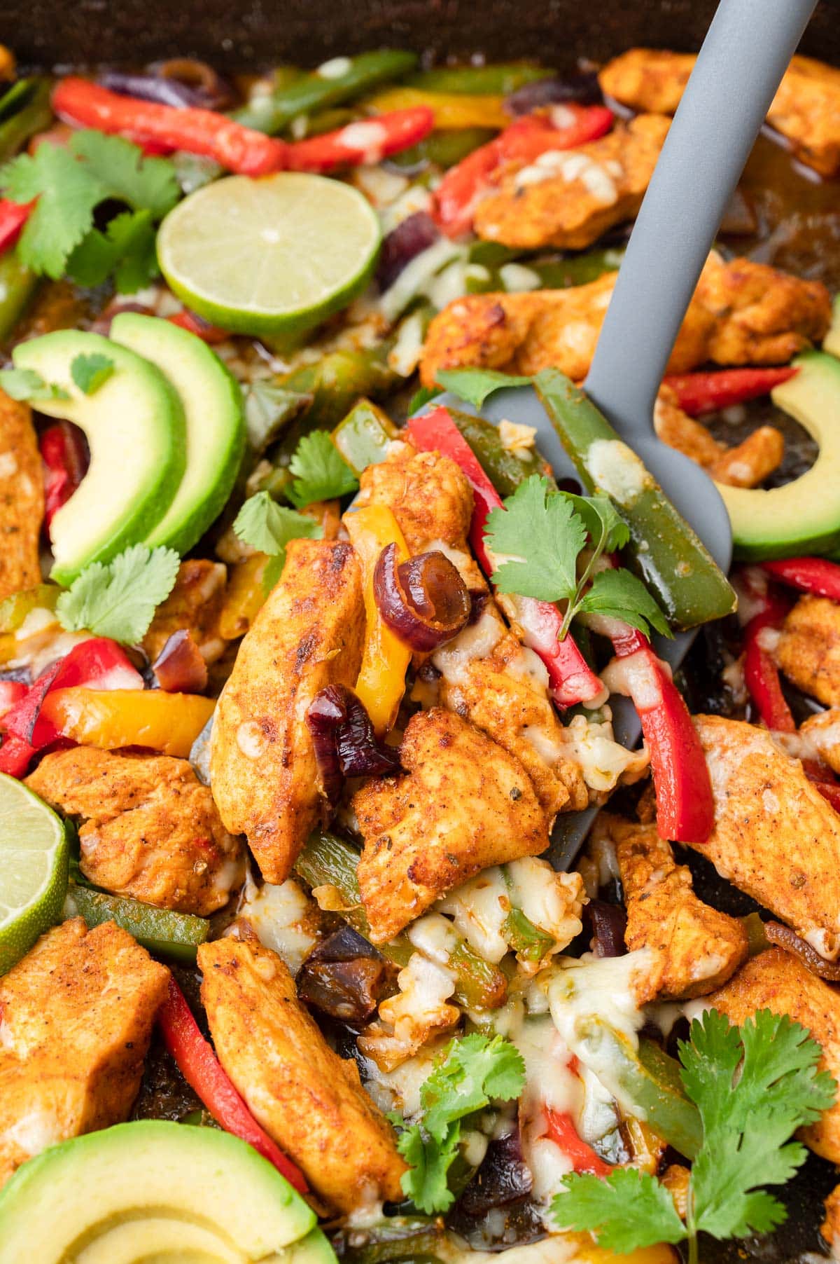 Sheet pan chicken Fajitas on a black baking sheet.