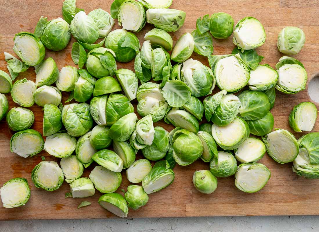 Cut in half Brussels sprouts on a wooden board.