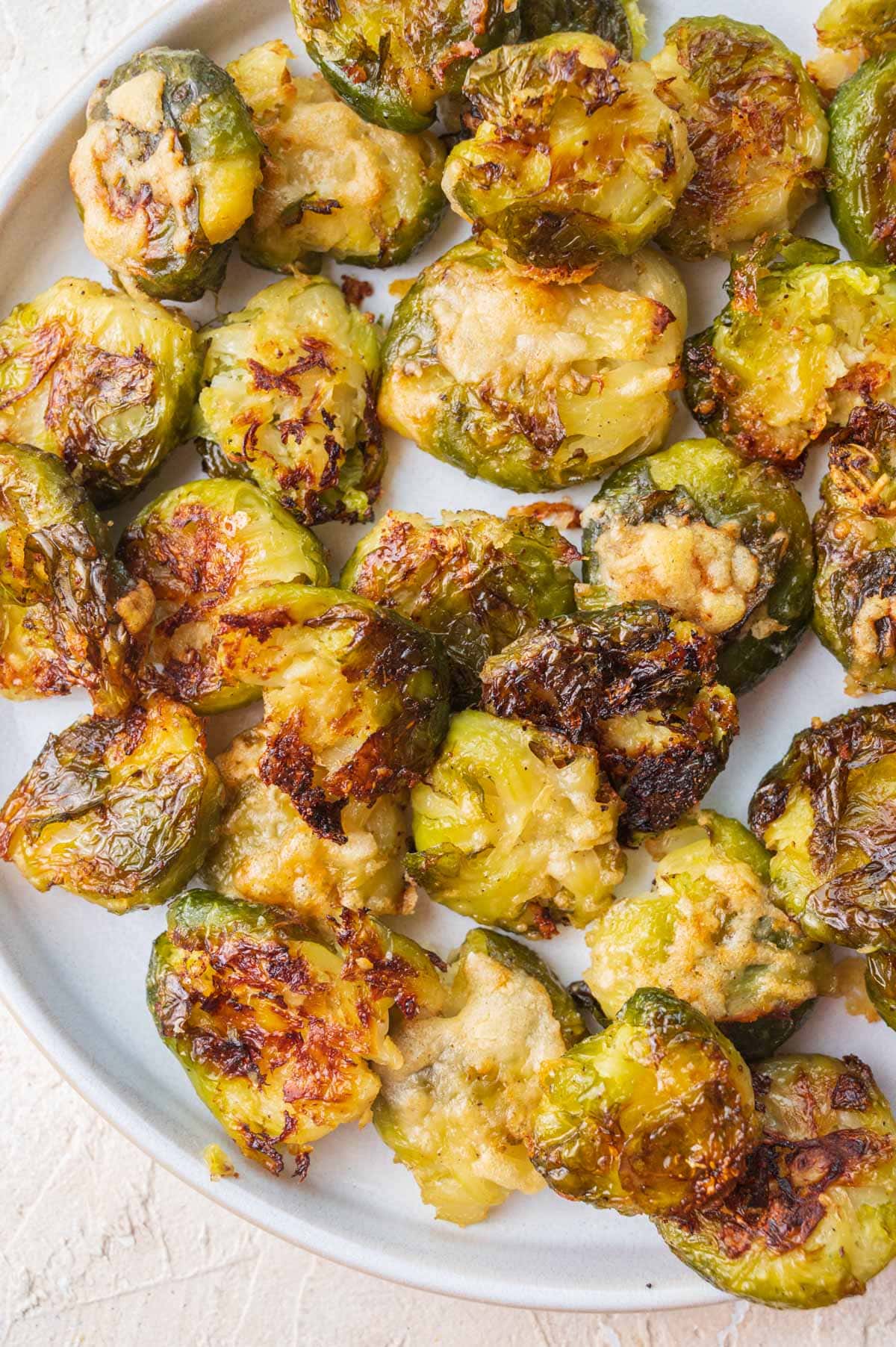 Smashed brussel sprouts on a white plate.