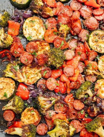 Roasted sausage slices and chopped vegetables on a baking sheet.