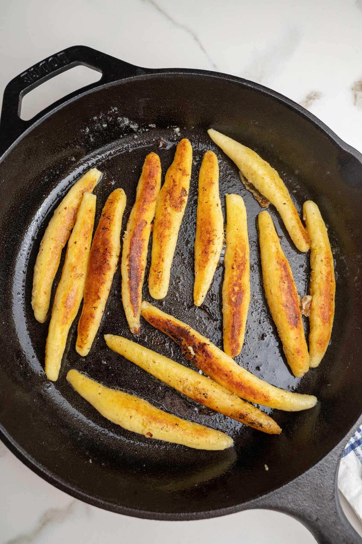 Pan-fried golden Schupfnudeln in a black cast iron pan.