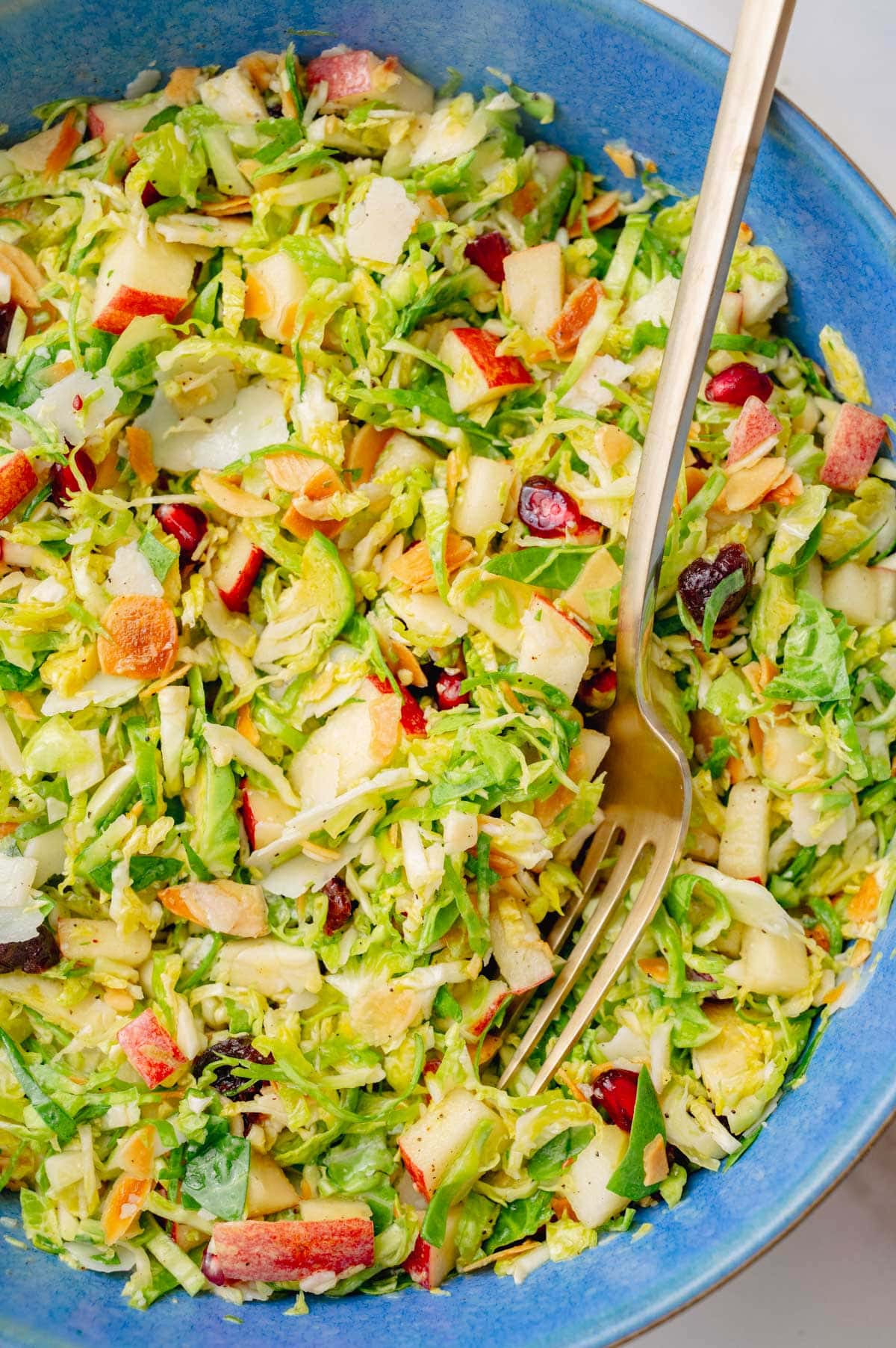 Shaved brussel sprouts salad in a blue bowl.