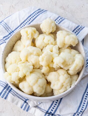 Steamed cauliflower florets in a white bowl.