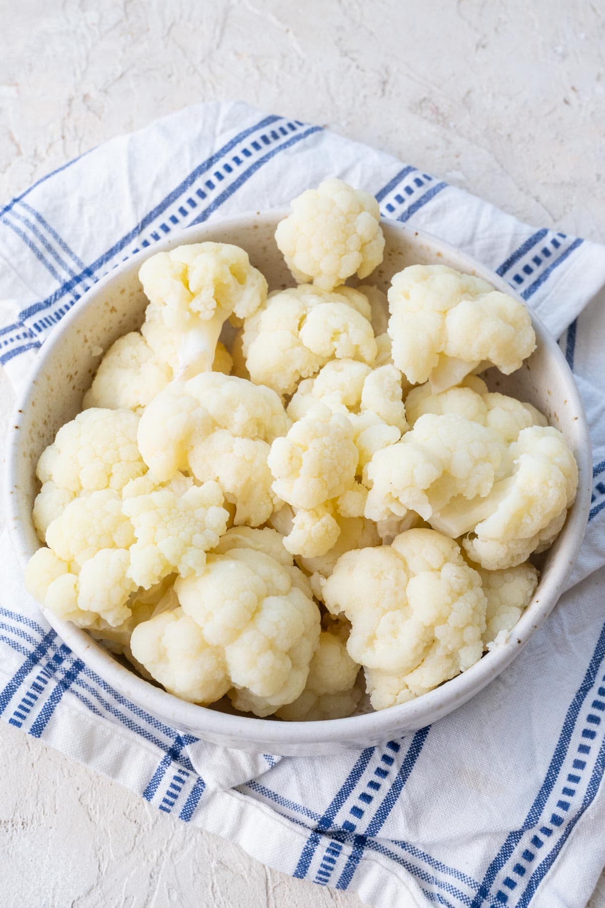 Steamed cualiflower florets in a white bowl.