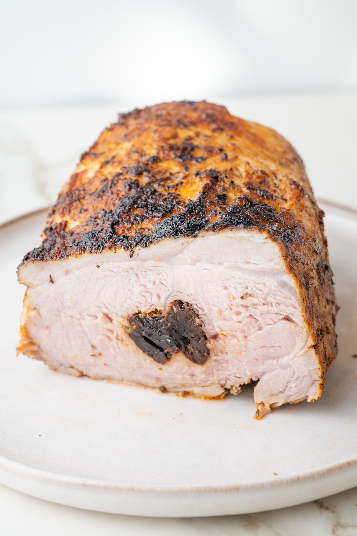 Polish pork loin roast stuffed with prunes cut in half on a plate.