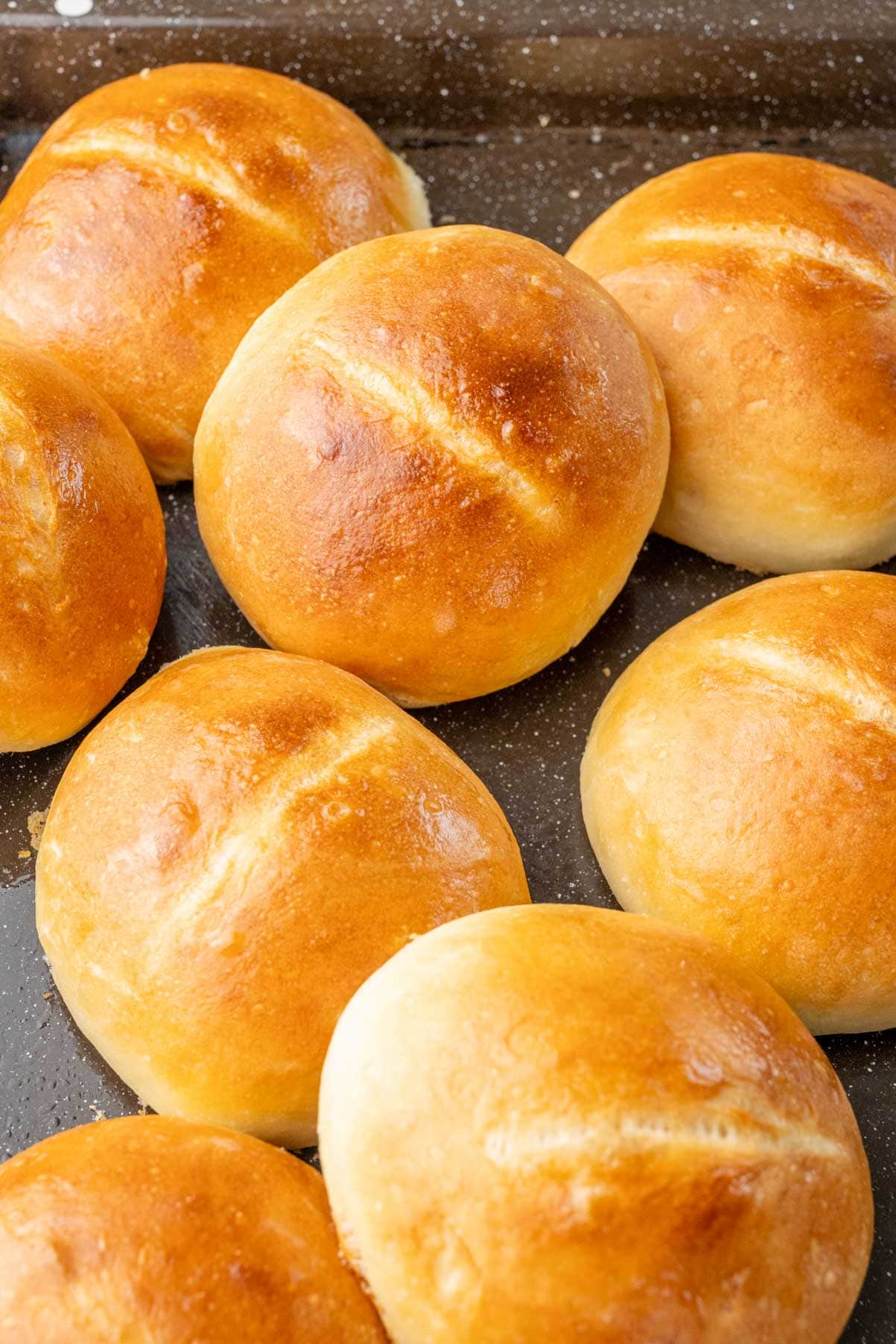 Brötchen bread rolls on a black baking sheet.