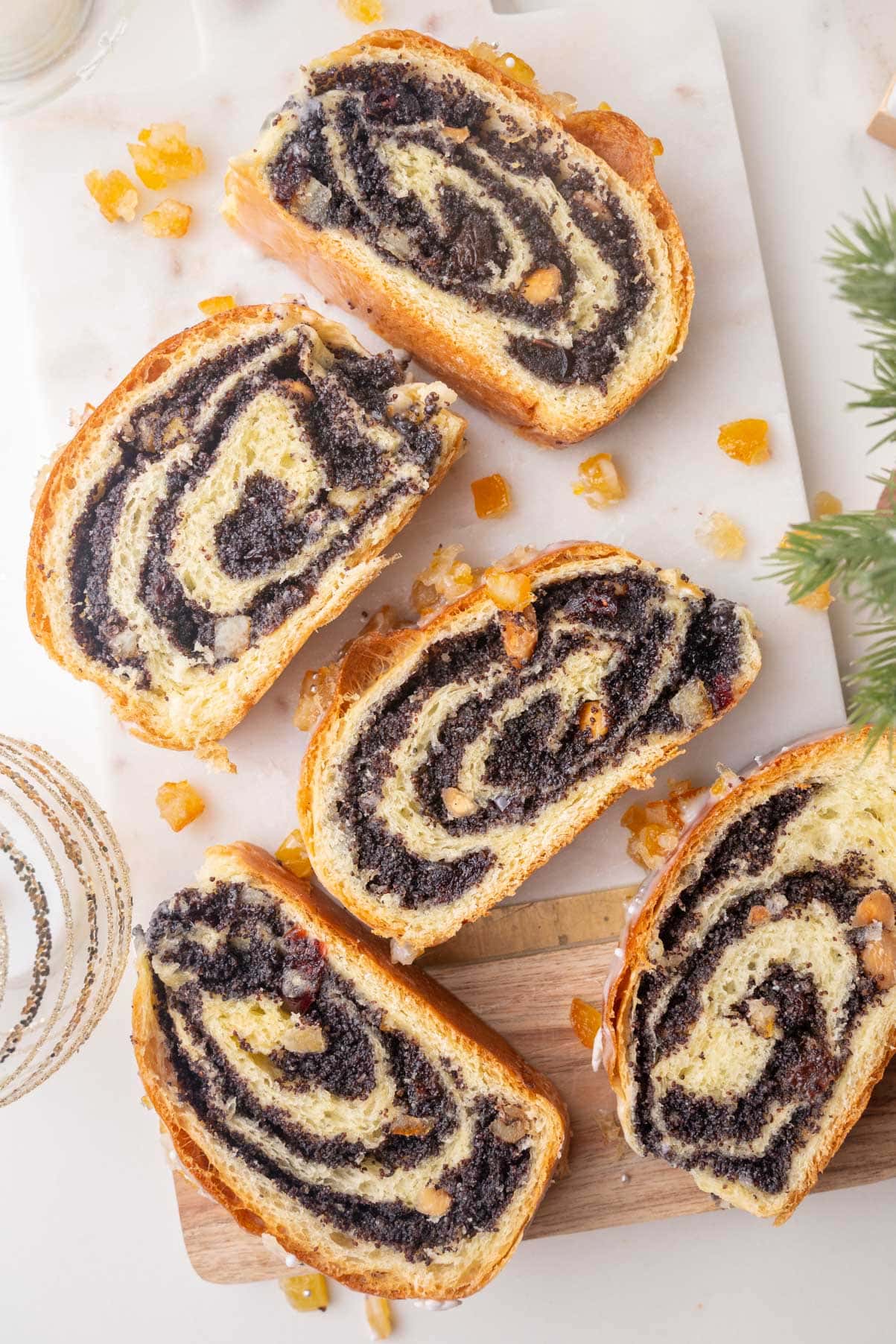 Slices of poppy seed roll on a marble board. Christmas decorations in the background.